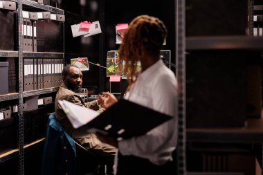 Özel dedektif suç dosyasının yanında duran suç dosyasını araştırırken ortağına yardım ediyor. Afro-Amerikan müfettişler kanıtları analiz ediyor ve büro ofisinde rapor veriyor.