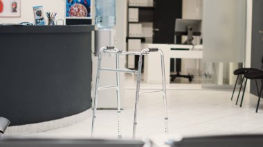 Hastane kayıt gişesine yerleştirilmiş yürüyüş çerçeveli klinik resepsiyon masası, sağlık sigortası. Koltuklu sağlık merkezi ve randevu formları.