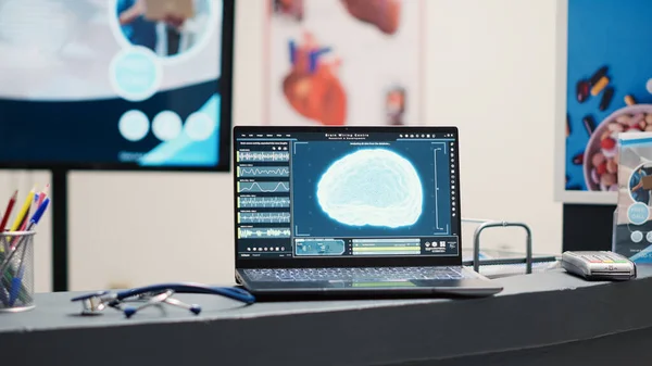 笔记本电脑在医疗诊断中心 候诊区的办公桌上显示神经系统 显示神经科学 X光和人脑分析扫描 疾病的空保健设施 — 图库照片