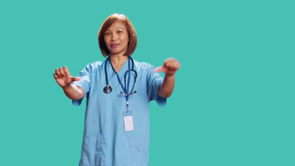 Üzgün Asyalı Hemşire Işteyken Işaret Veriyor Mavi Stüdyo Arka Planında — Stok video