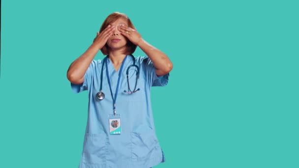 累了的Bipoc有护士用手掌捂住脸 工作了一天后精疲力竭 亚洲医疗保健专业人员需要离职 与外界隔绝在蓝色工作室的背景之下 — 图库视频影像