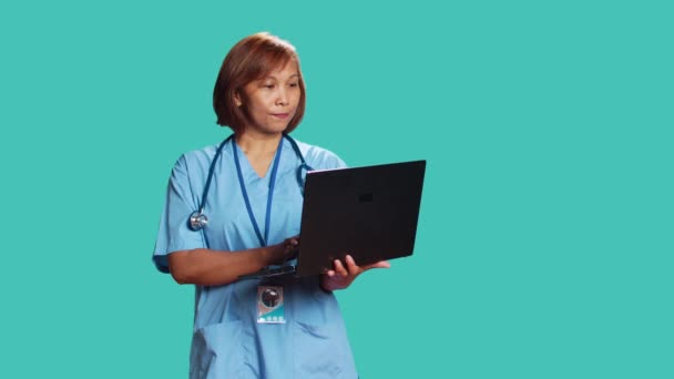 Focused Asian Nurse Typing Patient Data Laptop Finishing Medical Checkup — Stock Video