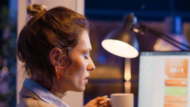 Danışman ajan ekranda mali tabloları incelerken esniyor, gece geç saatlere kadar proje teslim tarihine yetişmek için çalışıyor. Şirket gelişimini takip eden yorgun ve uykulu girişimci.