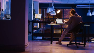 Danışman ajan gece geç saatlerde şirket raporlarını kontrol ediyor, yeni pazarlama stratejisi geliştirmek için fazla mesai yapıyor. Ofis müdürü mali grafik projesini monitörde planlıyor. El kamerasıyla..