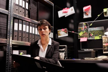 Polis memuru, suç mahallinin raporunu tartışmak üzere çevrimiçi görüntülü görüşme konferansında uzaktan çalışma arkadaşına suç davasını açıklıyor. Karanlık odadaki federal soruşturmalarda çalışan özel dedektif.