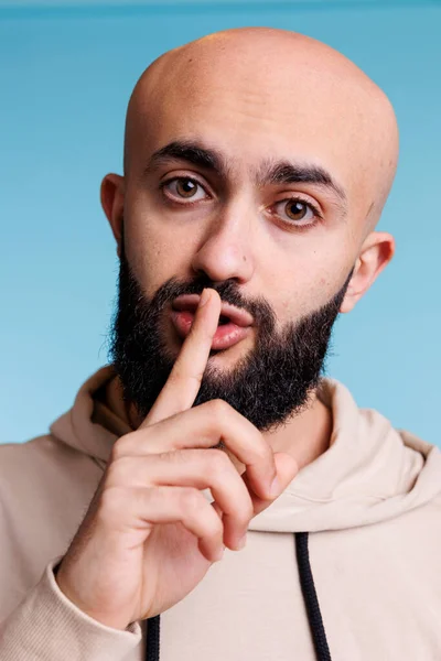 阿拉伯男子用手指捂住嘴唇 同时表现出沉默的姿态 并看着相机 在嘴上摆着食指的人 做着安静的手势 要求保持工作室的秘密肖像 — 图库照片