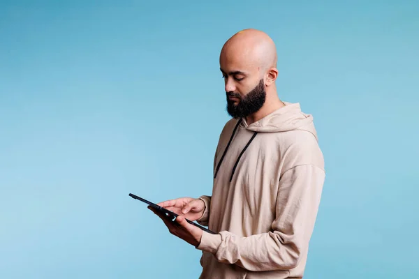 若い集中アラブ人の男性はデジタルタブレットで作業し オンラインメッセージを入力します 携帯型電子ガジェットでオンラインで読む人に焦点を当て インターネットページやテキストメッセージをスクロール — ストック写真