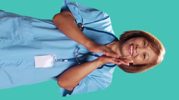 赞许微笑的护士愉快地拍手 满足于自己的成就 医疗专家们欢呼着 在工作时做着赞美的手势 被隔离在蓝色的工作室背景之外 — 图库视频影像