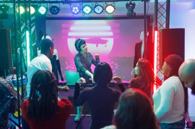 Dans pistinde parti yaparken elektronik müziği karıştırmak için DJ istasyonunu kullanan enerjik bir müzisyen. Gençler kulüp deneyimini ve konserde dans etmeyi seviyorlar