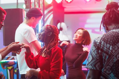 Gece kulübü partisinde dans eden ve dans pistinde kutlama yapan enerjik insanlar. Mutlu arkadaşlar eğleniyor ve diskotekte müzik ritmine ayak uyduruyorlar, gece eğlencesinin tadını çıkarıyorlar.