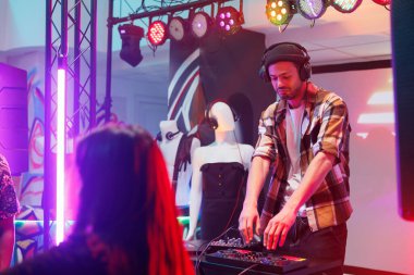 Kulaklıklı DJ, gece kulübündeki elektronik müzik konserinde şarkı karıştırıyor. Disko partisinde sahne ışıkları olan dijital panel kullanarak müzisyen performansı.