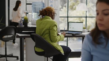 Business woman looking at annual report on laptop, planning corporate investment for marketing development. Startup worker checking data analytics on pc, taking notes on documents.