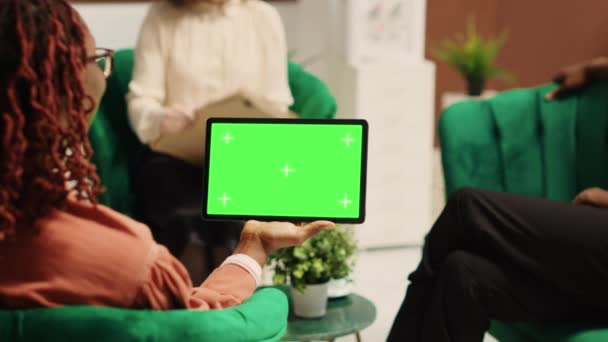 酒店大堂的游客在经理的协助下 手持彩色键绿色屏风在景观模式下模拟平板电脑 在办理入住手续时帮助客人的度假区管理员 — 图库视频影像