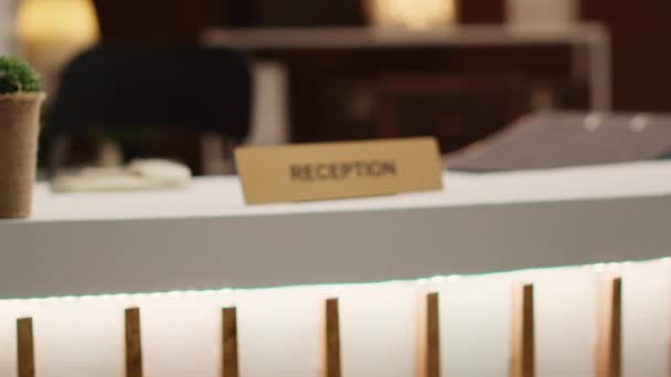 在时尚酒店大堂内空的干净桌子上显示出极其接近的接待标志的镜头 温暖舒适的乡村酒店业度假胜地入住柜台 — 图库视频影像