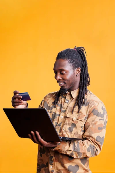 非洲裔美国人顾客在工作室购买时尚产品 在笔记本电脑上输入信用卡详情购买 笑着做网上购物 支付订单 — 图库照片