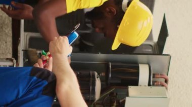 Hvac sistemindeki sıvı ve gazları kontrol etmek için profesyonel basınç kriterleme aracı oluşturan dikey video uzmanı Afro-Amerikan mekanik birikimi toprak ve toz tabakasını temizlerken,
