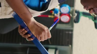 Dikey video Afro-Amerikan teknisyeni HVAC sistemi dışında yıllık bakım için görevlendirildi. Kırık iç parçaları arıyor. Yoğunlaştırıcı teftişi ve rapor yazma konusunda yetenekli bir telsizci.