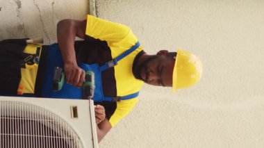 Dikey video ekip çalışması lisanslı askerler bozuk hvac sistemi üzerinde çalışmaya başlıyorlar, yoğunlaştırıcı bobin panelini söküyorlar. Uygun olmayan elektrik tesisatını kontrol etmek için havalandırmayı söken kalifiye elektrikçiler