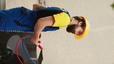 Dikey video yeteneği olan elektrikçi freon seviyelerini manifold metre ile ölçerken, Afrikalı Amerikalı meslektaşı çatı katlama merdiveninden indi.