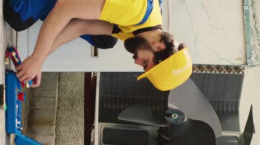 Rutin hvac sistem bakımı için görevlendirilmiş dikey video mühendisi işe başlamadan önce manometre montajı yapıyor. Tamirci soğutucu sızıntısı bulmaya çalışıyor.