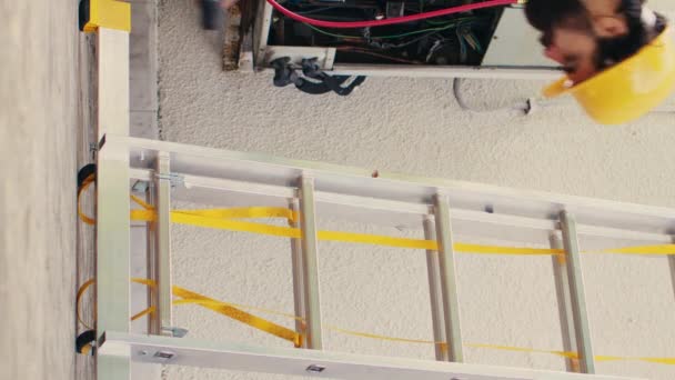 垂直ビデオ屋上のHvacシステムのメンテナンスを行うには 折り畳みはしごを登る技術機器とプロの制服で細心のメカニズム 専門家の労働者に確認を委託 — ストック動画