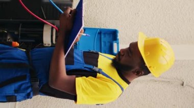 Klima soğutma soğutucu seviyelerini kontrol etmek için manifold sayaçlarıyla çalışan dikey video tamircileri, panoya yazı yazıyorlar. Açık havada barometre kriterleri kullanan usta işçiler.