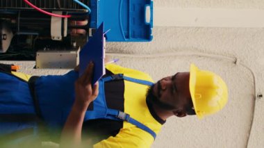 Klima soğutma soğutucu seviyelerini kontrol etmek için manifold göstergeleriyle çalışan dikey video uzmanları ekibi panoya sonuç yazıyorlar. Barometre kriterleme hvac kullanan yetenekli mekanikler