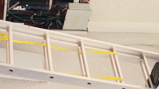 在完成屋顶Hvac系统的维修后 拥有电力钻头的垂直视频熟练专家从折叠梯子上下来 同时同事组装流量计检查氟利昂 — 图库视频影像