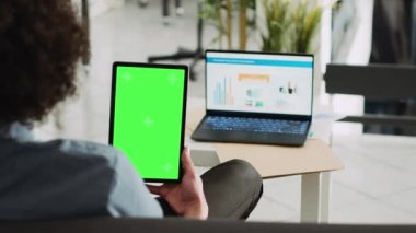 Yıllık istatistiklere ve krom anahtar görüntülerine bakan yeşil ekranlı analist holding cihazı, küçük işletme. İzole edilmiş şablon ekranı ve skorborda raporu ile çalışan girişimci.