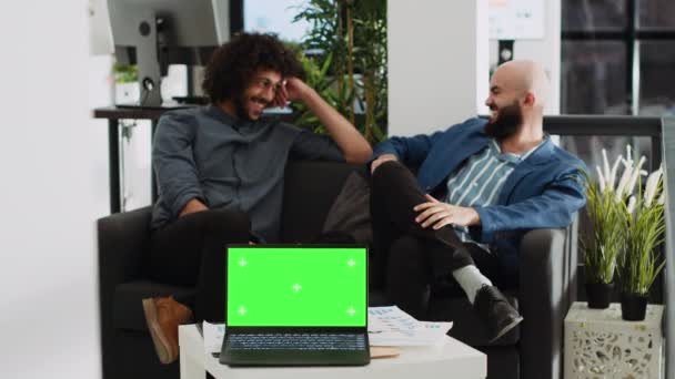 オフィスのノートパソコンに緑の画面が表示され ビジネスパートナーはプロジェクト管理について議論する コピースペースの概念を持つ独立したクロマキーテンプレート 現代的なオープンフロアのスタートアップ代理店 — ストック動画