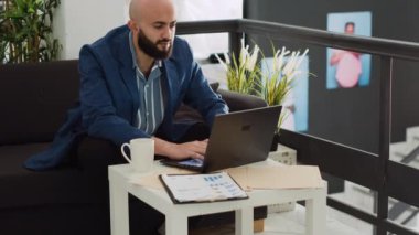 Şirket çalışanı başlangıç ofisinde aylık istatistikleri inceliyor, küçük işletme kârını artırmaya çalışıyor. İş adamı pazarlama bilgilerini toplamak için laptoptan rapora bakıyor..