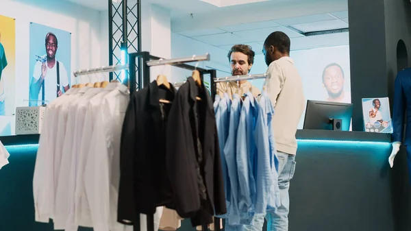 男性购物者在服装店的Pos终端购买时尚服装 年轻人在收银台和精品店的员工聊天 做小生意 手持射击 — 图库照片