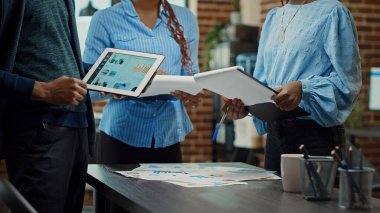 Meslektaşlar brifing sonuçlarını analiz etmek için tablet ve kağıt kullanıyorlar. Yeni iş vizyonu oluşturmak için istatistiklerle çalışıyorlar. Karı artırmak için planlama geliştirme stratejisi.