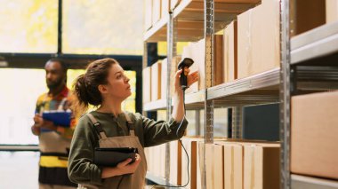 Depo çalışanı raflardaki paketleri tarıyor, depodaki ürün teftişi üzerinde çalışıyor. Depo envanteri sırasında raflardaki aksanları gözden geçirmek, perakende sevkiyat için siparişleri hazırlamak.
