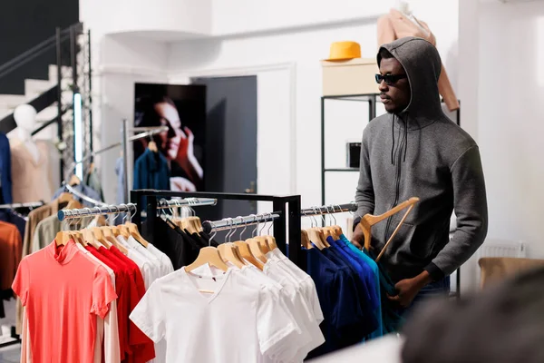 Afrykański Amerykański Złodziej Podejmuje Ryzyko Patrząc Modne Ubrania Przed Kradzieżą — Zdjęcie stockowe
