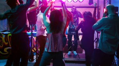 Bir grup arkadaş kulüpte eğleniyor, elektronik müzik eşliğinde parti yapıyor ve dans pistinin keyfini çıkarıyor. Genç erkekler ve kadınlar disko ışıklarıyla elektronik funk partisinde dans ediyorlar. El kamerasıyla..