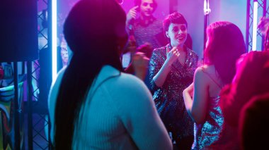 Havalı bir grup arkadaş partide eğleniyor, disko ışıkları altında eğleniyorlar. Gülümseyen insanlar dans edip dans pistinde zıplıyorlar, gece hayatı kutlama partisinin tadını çıkarıyorlar. El kamerasıyla..