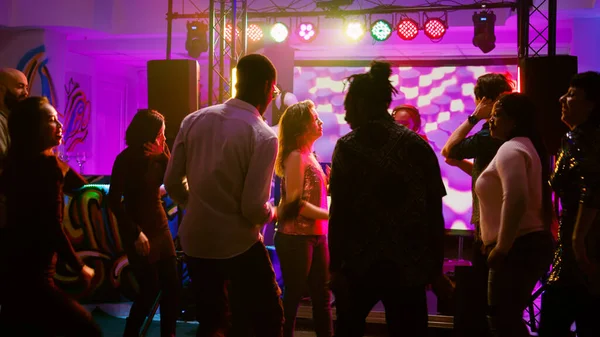 ファンキーなビートでダンスムーブを披露するクールなダンサーは ディスコで社交的な集まりで人々と楽しみを持っています ダンスフロアでパーティーを楽しむ人々のグループ お祝い 手持ち撮影 — ストック写真