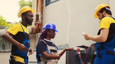 Qualified experts installing new outdoor air conditioner for home owner customer after replacing old unit. Capable electricians commissioned to optimize new HVAC system performance clipart