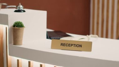 Zarif modern konukseverlik endüstrisinin kapanışı otel lobisinde masa başında. Boş karşılama yeri lobisi resepsiyon masası, kapıcı çanı mini fabrikanın yanında.