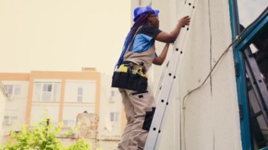 Elektrikli matkap ustası çatı hvac sisteminin bakımını bitirdikten sonra merdivenden iniyor. Klimayı kontrol etmek için görevlendirilmiş bilgili bir profesyonel.