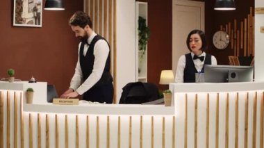 Otel resepsiyonunda randevu verileri alan turistleri karşılaştıran mutlu resepsiyonistler. Takım çalışanı profesyonel tatil köyü personeli şık bir tatil beldesinde kasada çalışıyor.
