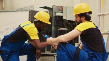 Hvac sistemindeki sıvı ve gazları kontrol etmek için profesyonel basınç kriterleme aracı oluşturma konusunda uzman. Afrikalı Amerikalı tamirci yoğunlaştırıcıda birikmiş toprak ve toz tabakasını temizliyor.