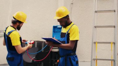 Klima soğutucu seviyelerini kontrol etmek için manifold sayaçlarıyla çalışan usta tamirciler, panoya yazı yazıyorlar. Barometre kriterleme açık hava hvac sistem aracı kullanan usta işçiler
