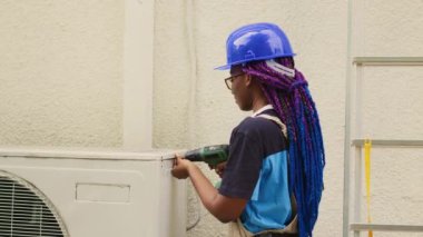 Çırak mekanik dissasembling açık hava klima metal üst bobin panel arızalı bileşenleri kontrol etmek için. Afrikalı Amerikalı teknisyen hasarlı yoğunlaştırıcıyı tamir ediyor.