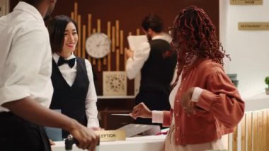 Tatil gezisini bitiren turistler, çıkış işlemleri sırasında neşeli arkadaş canlısı resepsiyonistlere oda kartı dağıtıyorlar. Mutlu misafirler otelden ayrılmaya hazırlanıyor.