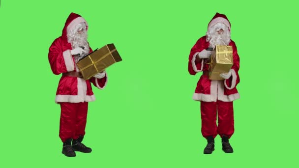 世界中の子供たちに贈り物を提供する準備をし スーツのスキャニングプレゼントボックスで聖ニック 若い男は赤い衣装でサンタのように行動し リボンでお祝いパッケージを保持 — ストック動画