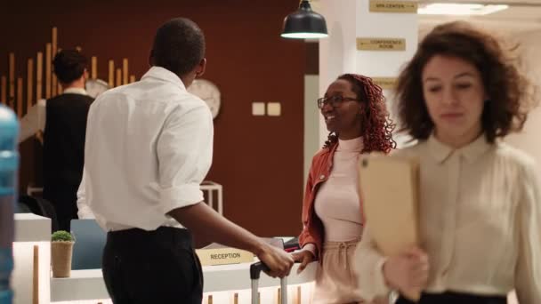 アフリカ系アメリカ人のカップルは 新婚旅行の成功後に豪華なホテルからチェックアウトします リゾートロビーのフレンドリーなフロントデスク受付でお客様をお手伝いします — ストック動画