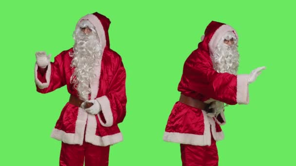 サンタ クラスは孤立した緑の背景の上で子供を愛撫し クリスマスの精神と積極性を広めるために甘い行動をとる傾向があります 男ドレスのような聖人ニックでXmas赤衣装 — ストック動画