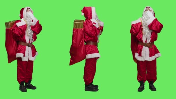 12月の休日のプレゼントやおもちゃで袋を運ぶことに疲れを感じて フルボディの緑の画面に対してあくびサンタスーツの眠そうな人 疲れを感じる聖ニックの具現化 — ストック動画